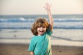 Excited cute kid boy walking the sea beach. Amazed surprised kids emotions.
