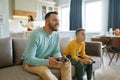 Dad and son playing video game while mom cooking on kitchen Royalty Free Stock Photo