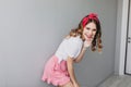 Excited dark-haired girl having fun during studio photoshoot. European pleased lady in pink skirt d