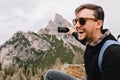 Excited dark-haired man in sunglasses resting in mountains after long climbing and sincere laughing. Outdoor portrait of