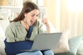 Excited disabled woman with broken arm reading news on laptop