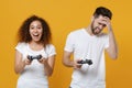 Excited displeased couple two friends european guy african american girl in white t-shirts posing isolated on yellow Royalty Free Stock Photo