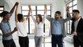 Excited diverse business team celebrate hands up corporate victory together.