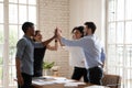 Excited diverse coworkers give high five celebrate success