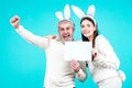 Excited Easter couple in bunny ears and rabbit costume on blue background isolated. Bunny couple celebrating easter