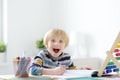 Excited elementary school boy doing homework at home. The child is passionate about the learning process. Delighted with what he Royalty Free Stock Photo