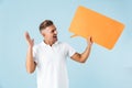 Excited emotional adult man posing  over blue wall background holding speech bubble Royalty Free Stock Photo