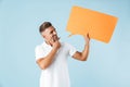 Excited emotional adult man posing isolated over blue wall background holding speech bubble Royalty Free Stock Photo