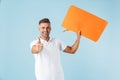 Excited emotional adult man posing  over blue wall background holding speech bubble Royalty Free Stock Photo