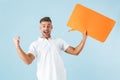 Excited emotional adult man posing isolated over blue wall background holding speech bubble Royalty Free Stock Photo