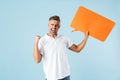 Excited emotional adult man posing  over blue wall background holding speech bubble Royalty Free Stock Photo