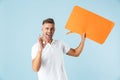 Excited emotional adult man posing  over blue wall background holding speech bubble Royalty Free Stock Photo