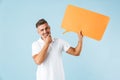 Excited emotional adult man posing  over blue wall background holding speech bubble Royalty Free Stock Photo