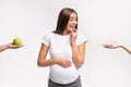 Excited Expectant Lady Choosing Between Doughnut And Apple Fruit, Studio Royalty Free Stock Photo