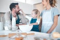 Excited family baking together.Caucasian family playing and baking. Little girl playfully putting flour on her fathers