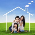 Excited family with a dream house at field Royalty Free Stock Photo