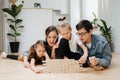 Excited family playing jenga on the floor, pulling tiles Royalty Free Stock Photo