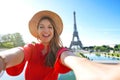 Excited fashion woman with red dress and hat has fun making self portrait with Eiffel Tower on the background in Paris, France Royalty Free Stock Photo