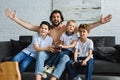 excited father and little sons sitting on sofa and playing video games together Royalty Free Stock Photo