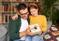 Excited  father  receiving gift box from young loving girl daughter on holiday while sitting together on sofa Royalty Free Stock Photo