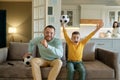 Excited father and son cheering and watching football match at home Royalty Free Stock Photo