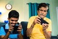 Excited father and son playing video game on mobile phone at home while sitting on sofa - concept of entertainment Royalty Free Stock Photo