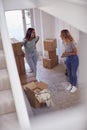 Excited Female Couple Carrying Boxes Through Front Door Of New Home On Moving Day Royalty Free Stock Photo