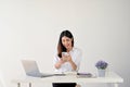 Excited female office worker looking at her phone screen while sitting at her desk Royalty Free Stock Photo