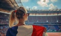 An excited female sports spectator holding a france flag in a sports stadium