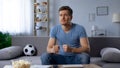 Excited football fan holding his fists for good luck, supporting national team