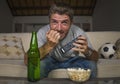 Excited football supporter man watching soccer game on television at home sofa couch in stress and emotion eating popcorn and Royalty Free Stock Photo
