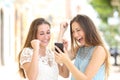 Excited friends checking online good news in a phone