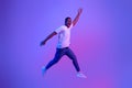 Excited Funny Black Guy Jumping Up In Neon Light Over Purple Background Royalty Free Stock Photo