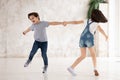 Excited funny kids siblings holding hands spinning playing at home