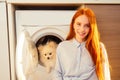Excited funny redhaired girl sitting next to her adorable fluffy spitz inside the washing machine at home . spa day for Royalty Free Stock Photo
