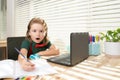 Excited funny schoolboy pupil does homework in school class. Writes text from laptop notebook. Royalty Free Stock Photo