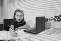 Excited funny schoolboy pupil does homework in school class. Writes text from laptop notebook. Royalty Free Stock Photo