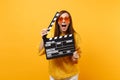 Excited funny young woman in fur sweater and orange heart eyeglasses holding classic black film making clapperboard Royalty Free Stock Photo