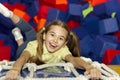 Excited girl climbing rope ladder over soft cube pit at indoor playground, overhead view Royalty Free Stock Photo