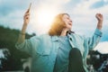 Excited girl dancing and listening music with headphones and smart phone in the street at sunset Royalty Free Stock Photo