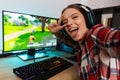 Excited girl gamer sitting at the table, playing online games