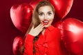 Excited young woman with red heart balloons. Surprised girl with red lips makeup, long curly hair andExcited girl on red heart Royalty Free Stock Photo