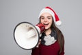 Excited woman in santa hat holding megaphone over grey background Royalty Free Stock Photo