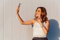 Excited girl showing a peace sign while taking a selfie on mobile phone Royalty Free Stock Photo