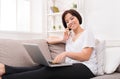 Young smiling beautiful woman with phone and laptop on the sofa Royalty Free Stock Photo