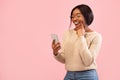 Excited Girl Using Smartphone Holding Finger On Chin, Pink Background Royalty Free Stock Photo