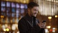 Excited guy messaging mobile phone on street. Cheerful man using phone outdoors.