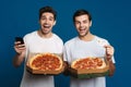 Excited handsome guys using cellphone while showing pizza and credit card