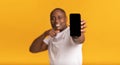 Excited happy adult african american man showing smartphone with blank screen to camera