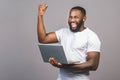 Excited happy afro american man looking at laptop computer screen and celebrating the win isolated over grey background Royalty Free Stock Photo